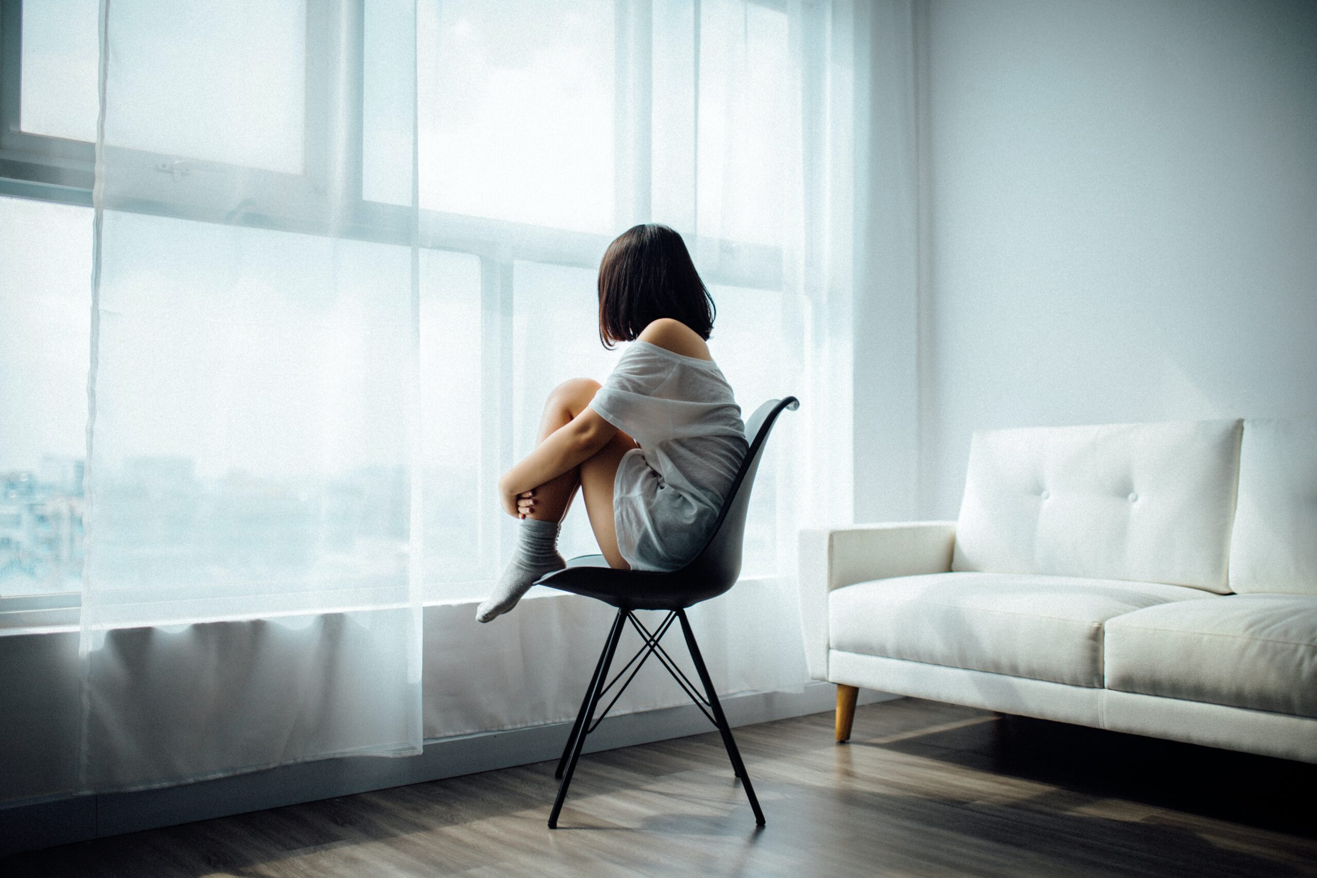 woman sitting in a chair staring out of a window contemplating if she's lacking self-awareness