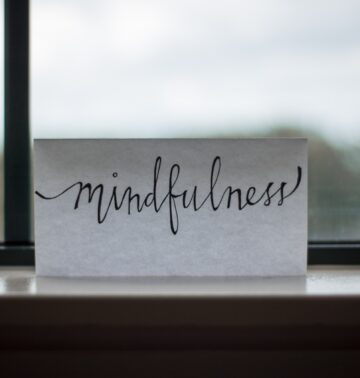 the word mindfulness written on a white piece of paper in front of a window for an article on how to protect your peace